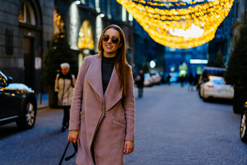 Obraz premium Beautiful young caucasian woman standing next standing in luxury district in city downtown. Stylish female model wearing sunglasses photographed in luxury district.