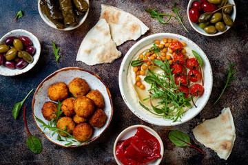 Arabic traditional cuisine. Middle Eastern meze with pita, olives, hummus, stuffed dolma, falafel balls, pickles. Mediterranean appetizer party idea