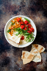 Homemade hummus with roasted cherry tomatoes and pita bread. Middle Eastern traditional and...