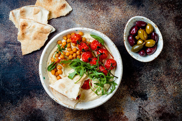 Homemade hummus with roasted cherry tomatoes, olives and pita bread. Middle Eastern traditional and authentic arab cuisine.