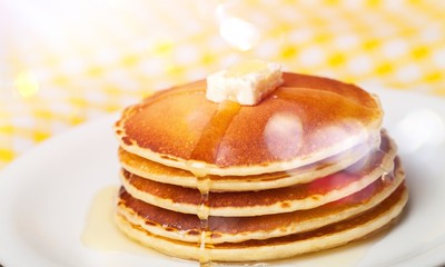 Stack of Small pancakes in syrup on background