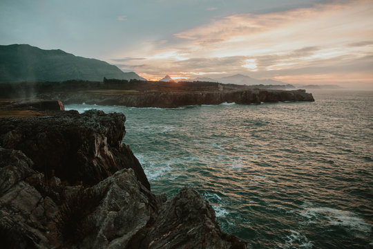 Picturesque view of high shore near stormy sea and beautiful cloudy sky at sunset in Bufones de Pria, Asturias, Spain