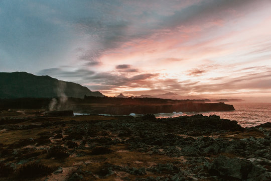 Picturesque view of high shore near stormy sea and beautiful cloudy sky at sunset in Bufones de Pria, Asturias, Spain