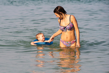 young mother swims with her son in the sea