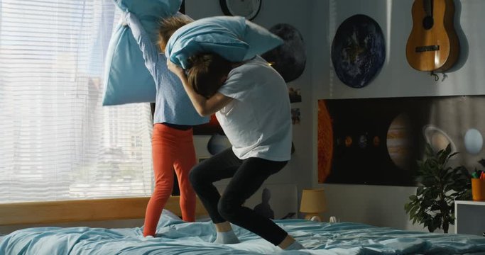 Boy and girl playing pillow fight on bed