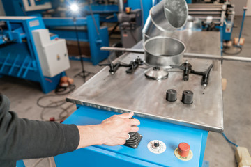 Worker controls the machine. Production rolling tool, electric machine. the production of ventilation and gutters. Tool and bending equipment for sheet metal.