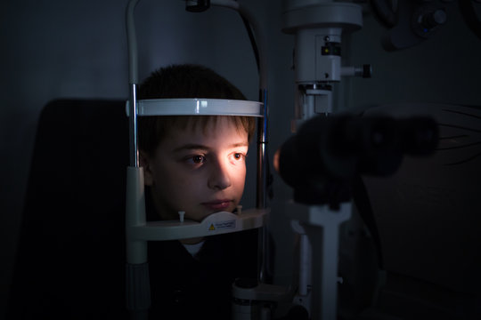 Optician testing a boy's eyes with optometry devices