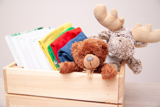 Donation Concept. Donate Box With Kids Clothes, Books, School Supplies And Toys. Teddy Bear And Moose Toy.