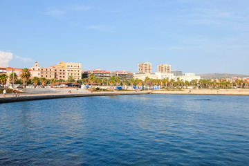 Fototapeta na wymiar Civitavecchia, Italy. View View of the embankment of Civitavecchia with green palm trees, blue sky, old typical roman houses and promenade along the coast in Lazio, Italy.