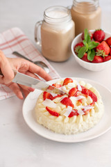 womens hand cut with a knife cake. Delicate strawberry cheesecake with coconut. Delicious homemade cake with Fresh berries on light table