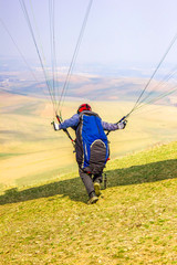 Man with a paraglider makes a run from the mountain