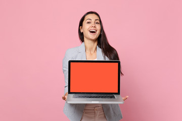 Portrait of laughing young woman in striped jacket holding laptop pc computer with blank empty screen isolated on pink pastel background. People sincere emotions lifestyle concept. Mock up copy space.