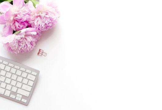 Feminine, styled photo with pink peonies and keyboard flatlay. For bloggers and creative businesses. With white space for text or product.