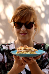 Young woman holding a plate with croissant, egg, ham and cheese sandwich. Selective focus.