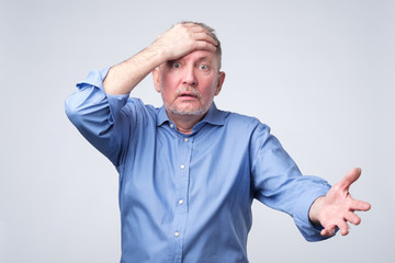 Naklejka premium Senior caucasian man surprised with hand on head.