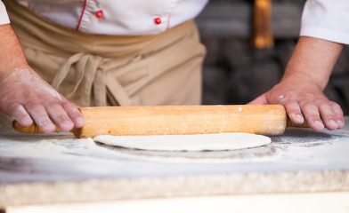 cook preparing pizza in a restaurant.
