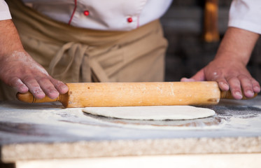 cook preparing pizza in a restaurant.