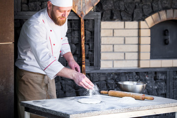 cook preparing pizza in a restaurant.