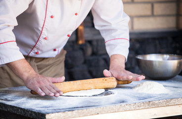 cook preparing pizza in a restaurant.