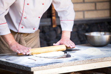 cook preparing pizza in a restaurant.