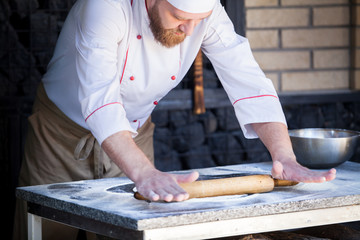 cook preparing pizza in a restaurant.