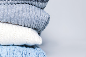 Stack of cozy comfortable homely clean washed knitted sweaters in pastel colors, laundry and washing clothes concept with copy space