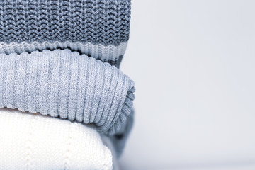 Stack of cozy comfortable homely clean washed knitted sweaters in pastel colors, laundry and washing clothes concept with copy space