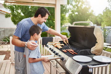 father teaching son how to grill hot dogs and bonding