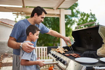 father teaching son how to grill hot dogs and bonding - Powered by Adobe