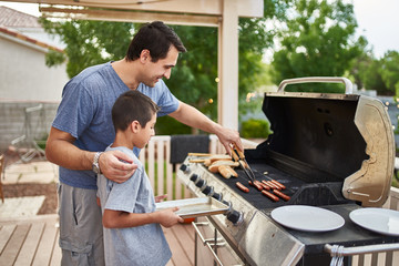 father teaching son how to grill hot dogs and bonding