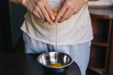  broken egg in hands, yolk falling down. Closeup. man is prepari