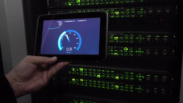 IT engineer measures network speed with a tablet computer in hand. LEDs blink. On background server racks. There is vibration in the video. Concept 3.0