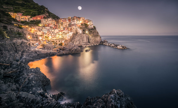 A waxing gibbous moon rises over the town of Manarola, which is part of the Cinque Terre region in Liguria on the coast of Italy.