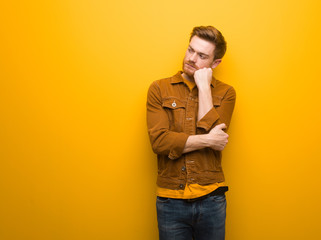 Young redhead man thinking of something, looking to the side