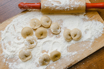 Make dumplings from dough and flour. Chopping board with rolling pin