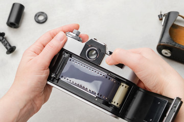 Hands loading film into retro SLR camera. - obrazy, fototapety, plakaty