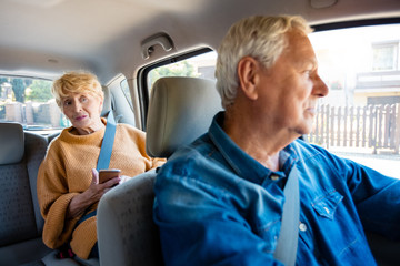 Senior woman traveling with male driver in taxi