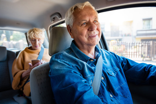 Confident male driver with senior woman in taxi
