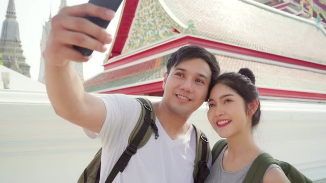 Asian blogger couple travel in Bangkok, Thailand, sweet couple using mobile phone selfie photo view while spending sweet time in holiday trip in sunset. Couple travel in city concept.