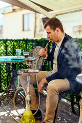 Handsome man chiling out while smoke hookah