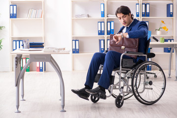 Young male employee in wheelchair working in the office 