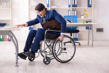 Young male employee in wheelchair working in the office 