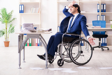 Young male employee in wheelchair working in the office 