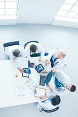 Medical team sitting and discussing at table, top view