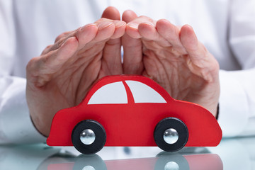 Businessman's Hand Protecting Red Toy Car