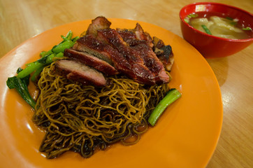 Close-up view of the wantan mee served with soy sauce,roast pork and vegetable. It is a Cantonese Chinese cuisine.