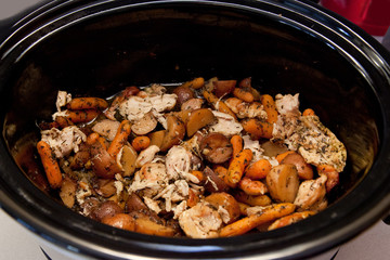 Chicken stew cooking in a black slow cooker, ready for a delicious healthy meal 