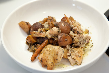 Chicken stew in a white bowl on top of the stove ready to be eaten