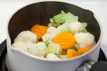 Frozen veggies in a small pot on top of the stove 