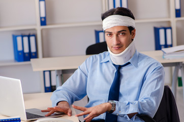 Young injured male employee working in the office 